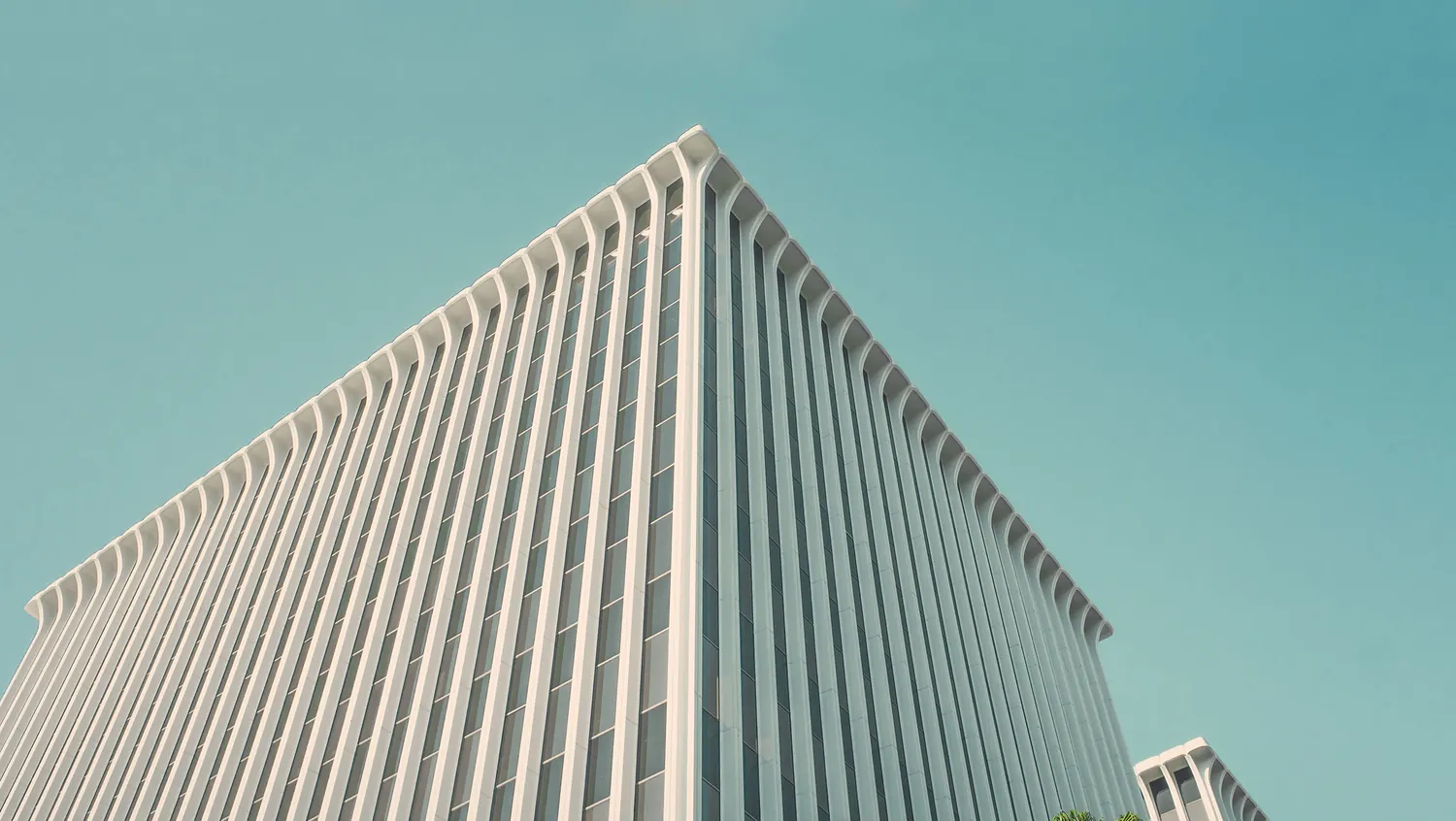 A modernist office tower photographed from below against a pale sky.